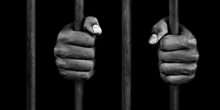 hands of a prisoner on prison bars